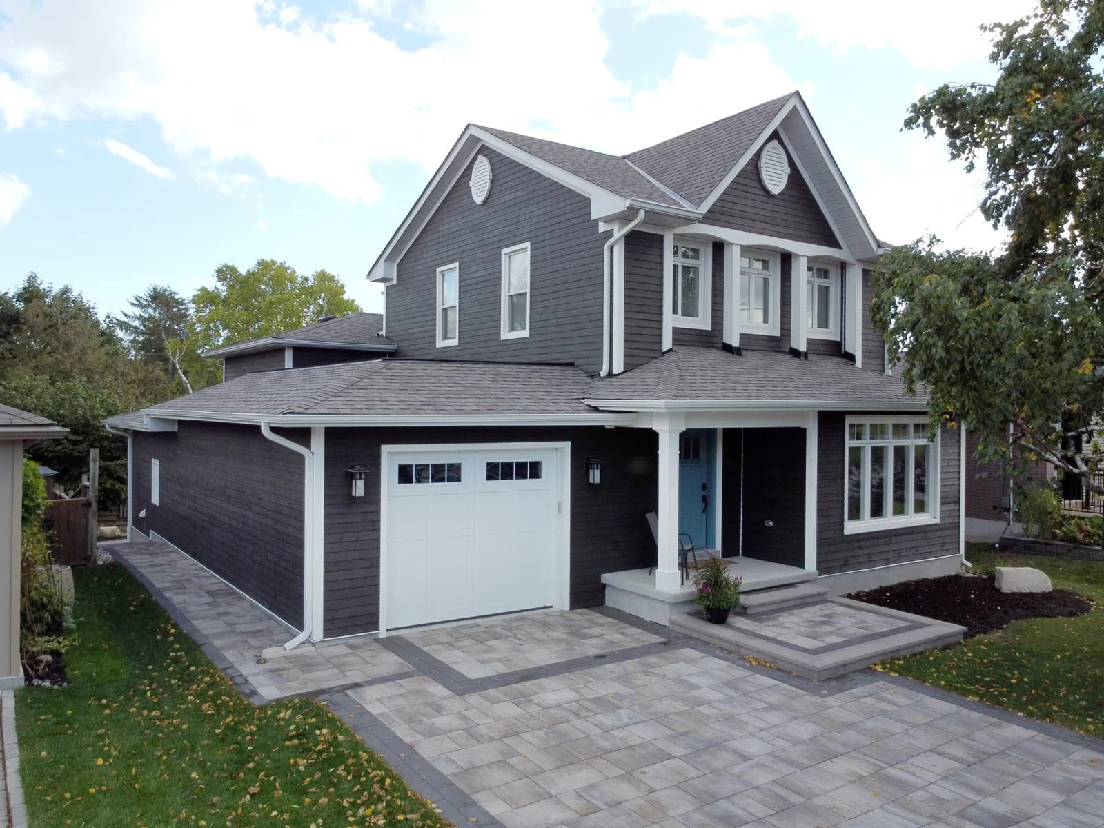 Finished second-storey addition with a new attached garage, grey siding and white trim, by CCS Group