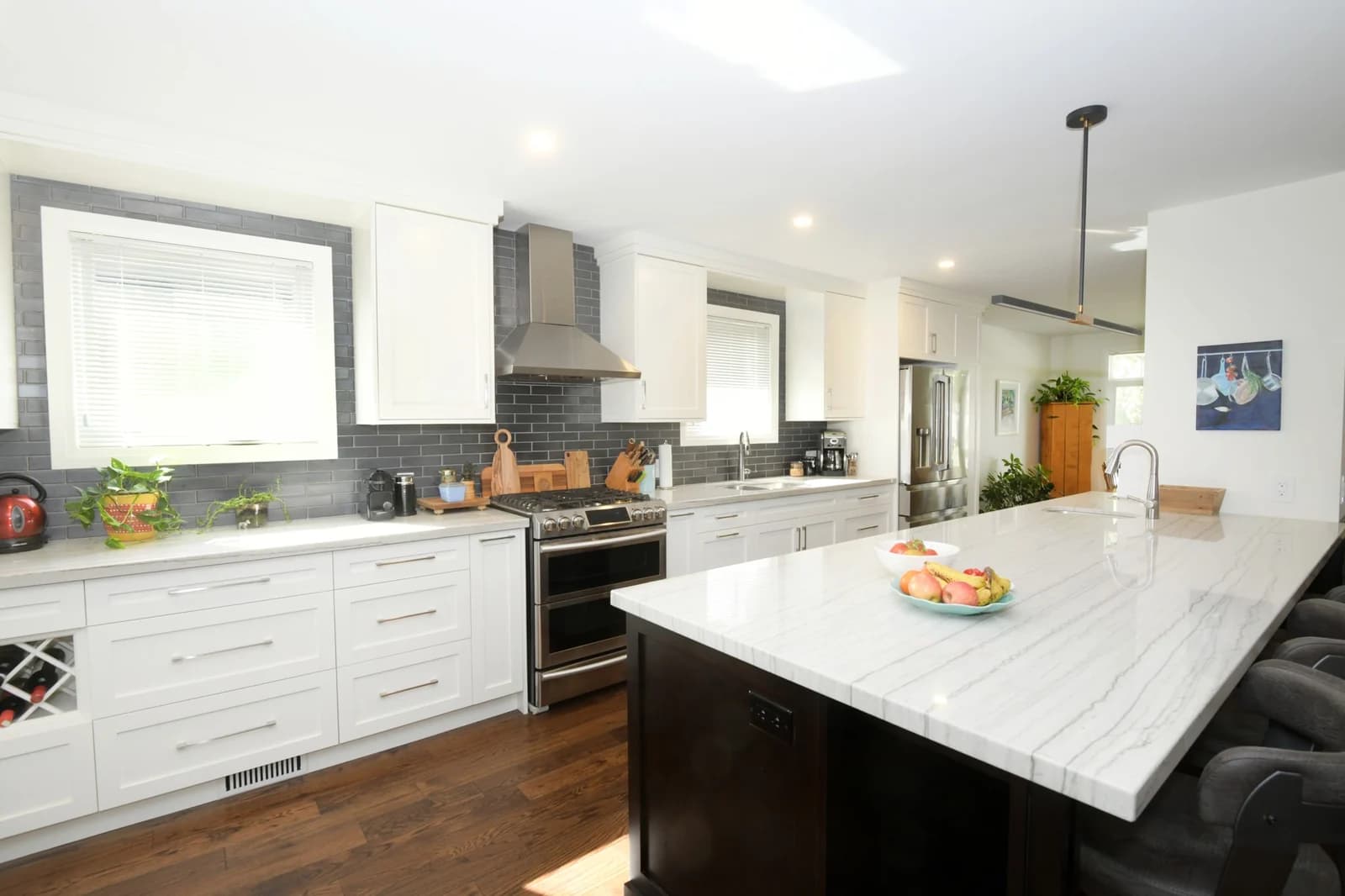 Open kitchen with island and dark-tile backsplash on the main floor of the addition project