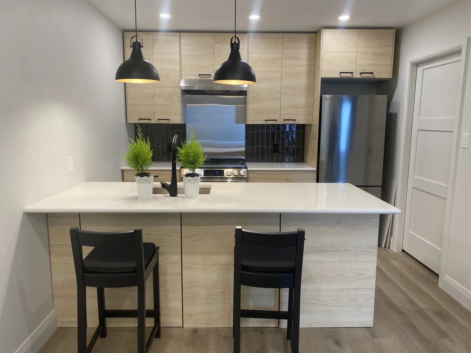 Laneway suite kitchen with island, oak cabinets and black tile